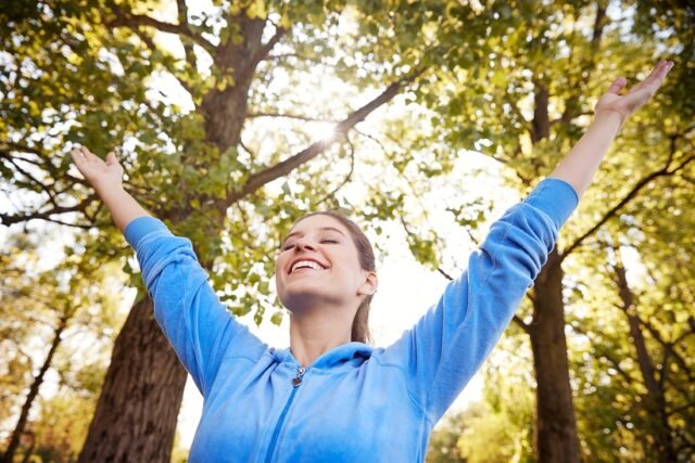 Woman Outdoors In Fitness Clothing Stretching Arms And Celebrating Nature