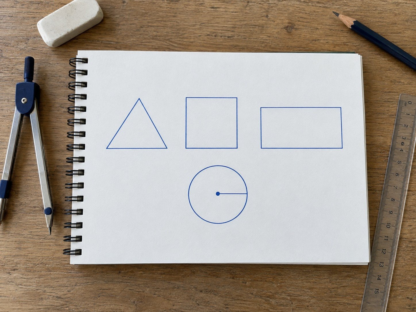 Geometrijske figure, šestar i lenjir na papiru